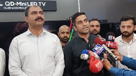 A TCL spokesperson speaking to a bank of TV microphones at a store launch